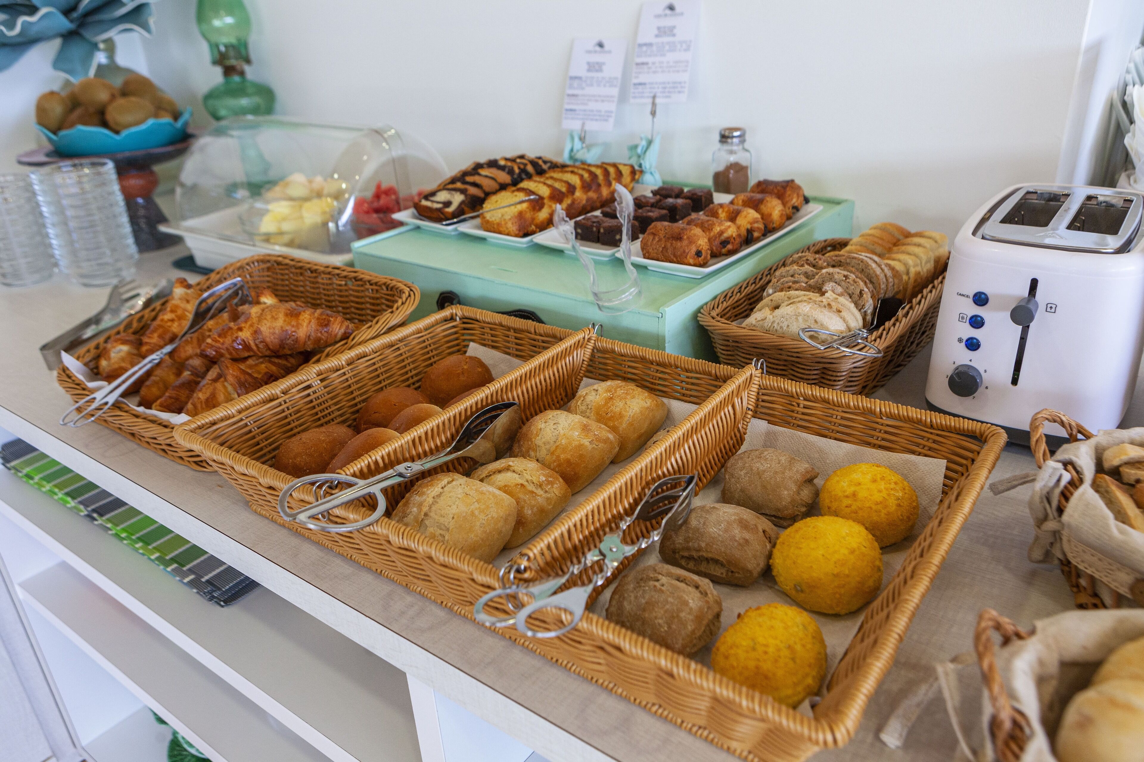 A buffet with various breads, pastries, and fruits.