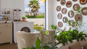 Una zona de bar con un letrero que dice "Honesty Bar", una barra blanca con un letrero y vistas a una palmera y un edificio a través de la ventana.