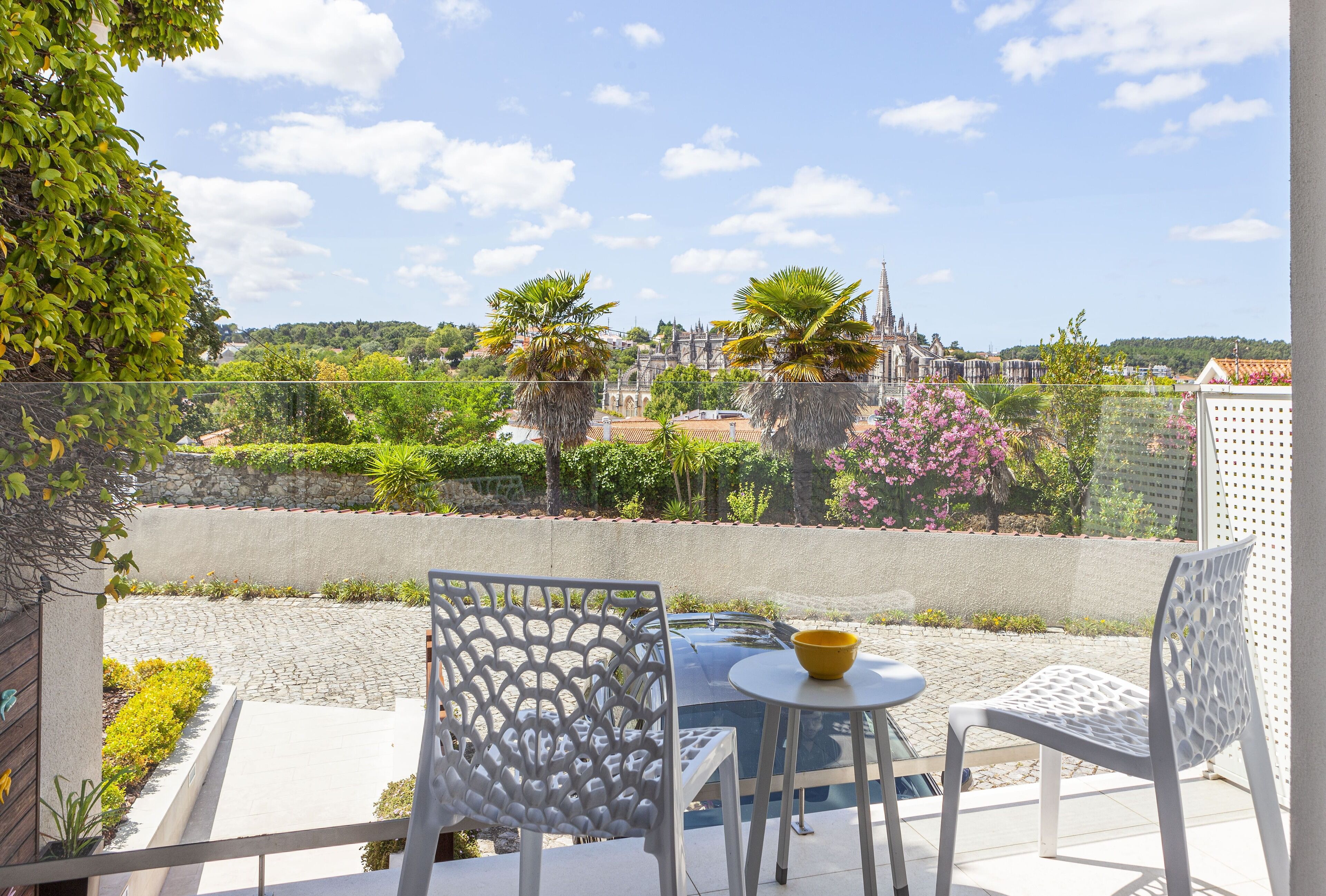 Una terraza con una mesa y sillas, vista a un paisaje urbano y cielo despejado.