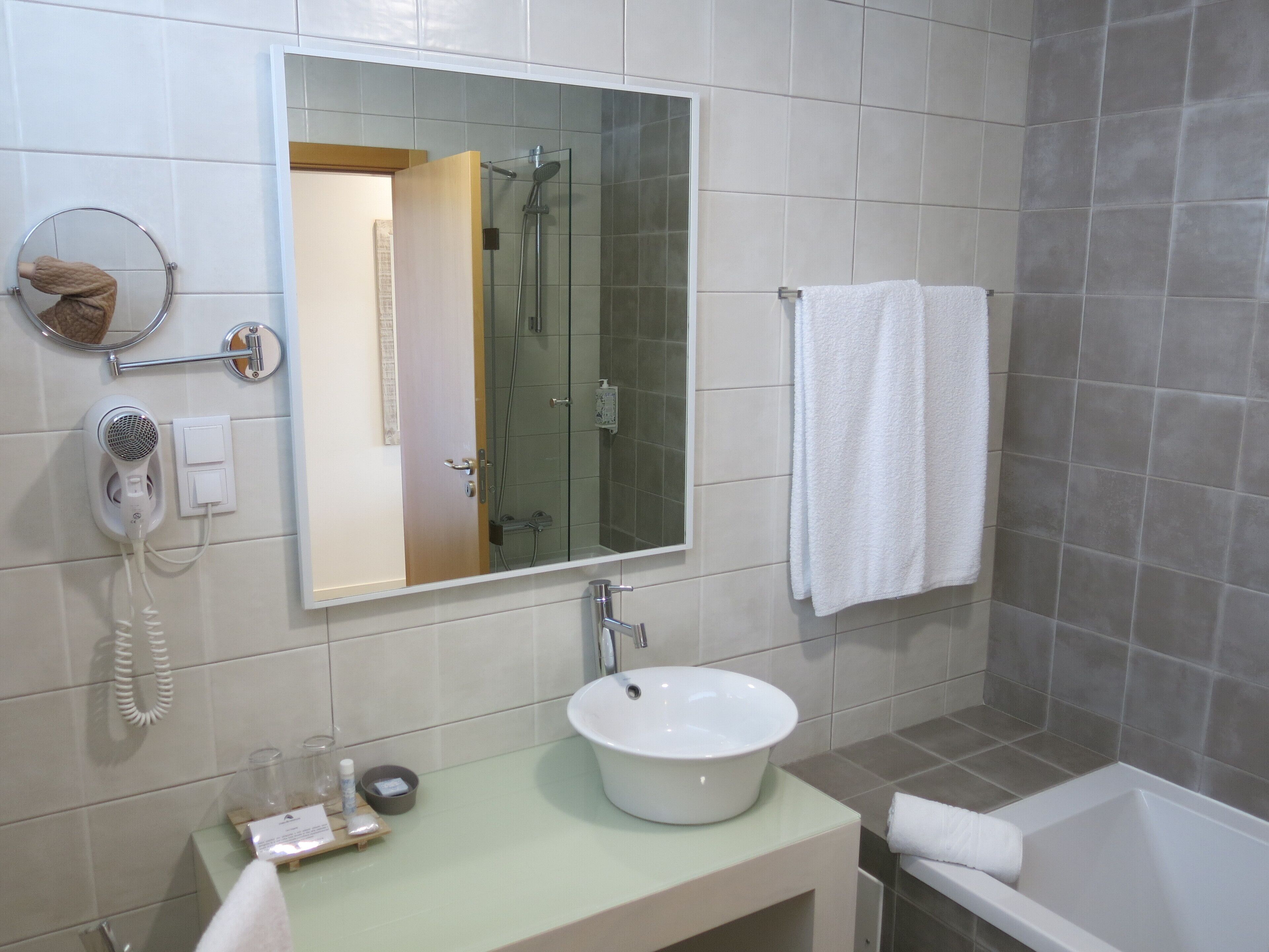 A bathroom with a sink, mirror, towel rack, and shower.