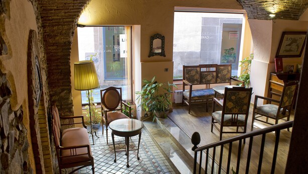 Un interior acogedor con suelo de baldosas, muebles de madera y una escalera que sube a un nivel superior.