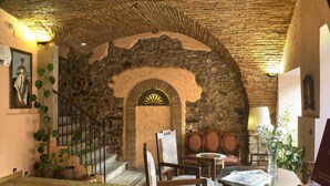 Un interior rústico con un arco de piedra, muebles de madera y plantas en macetas.