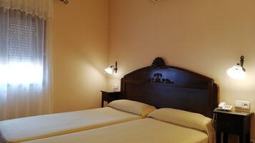 Une chambre d’hôtel avec deux lits, une table de chevet avec un téléphone, des lampes fixées au mur et un appareil de climatisation.