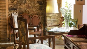 Una habitación rústica con paredes de piedra, muebles de madera, una lámpara y un florero con flores.