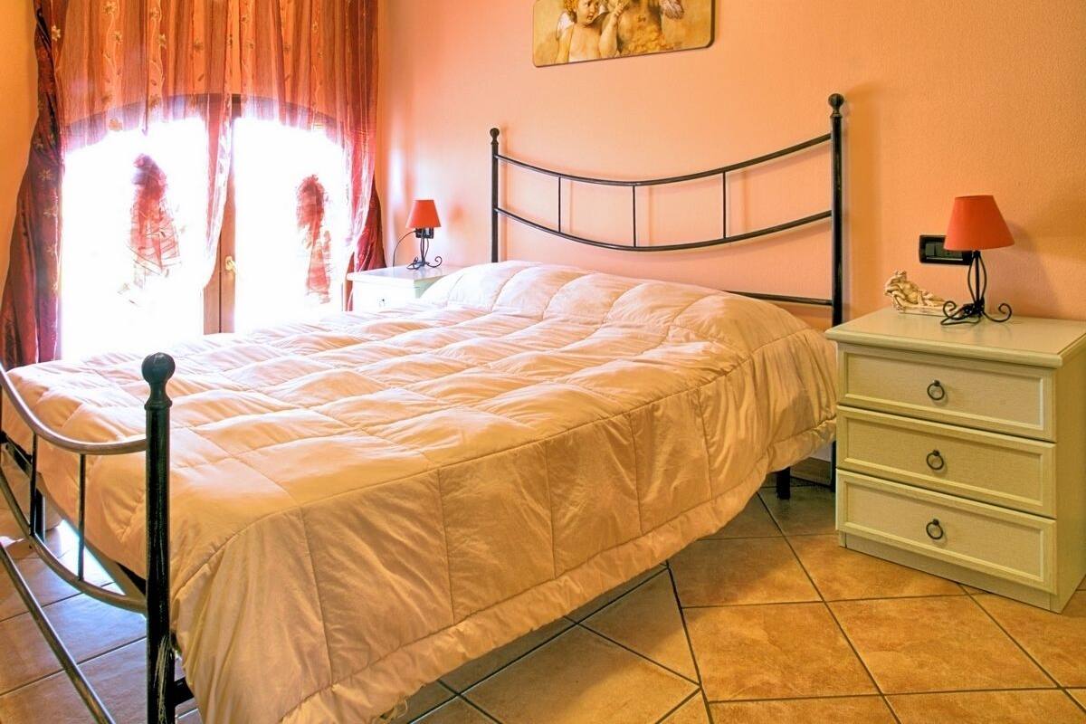 Une chambre à coucher avec un lit, une table de chevet, une lampe et un tableau au mur.