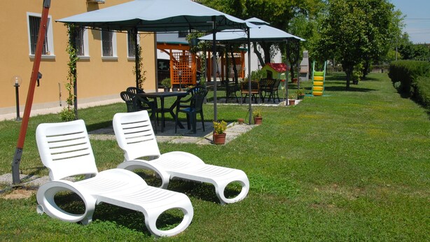 Mobiliario exterior con sombrillas, una estructura de juegos e igual una zona de césped.