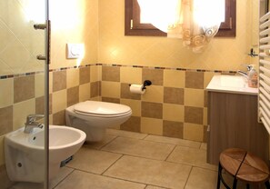 A bathroom with a toilet, bidet, sink, and a window with curtains. - Agriturismo Il Melograno (Mestre)