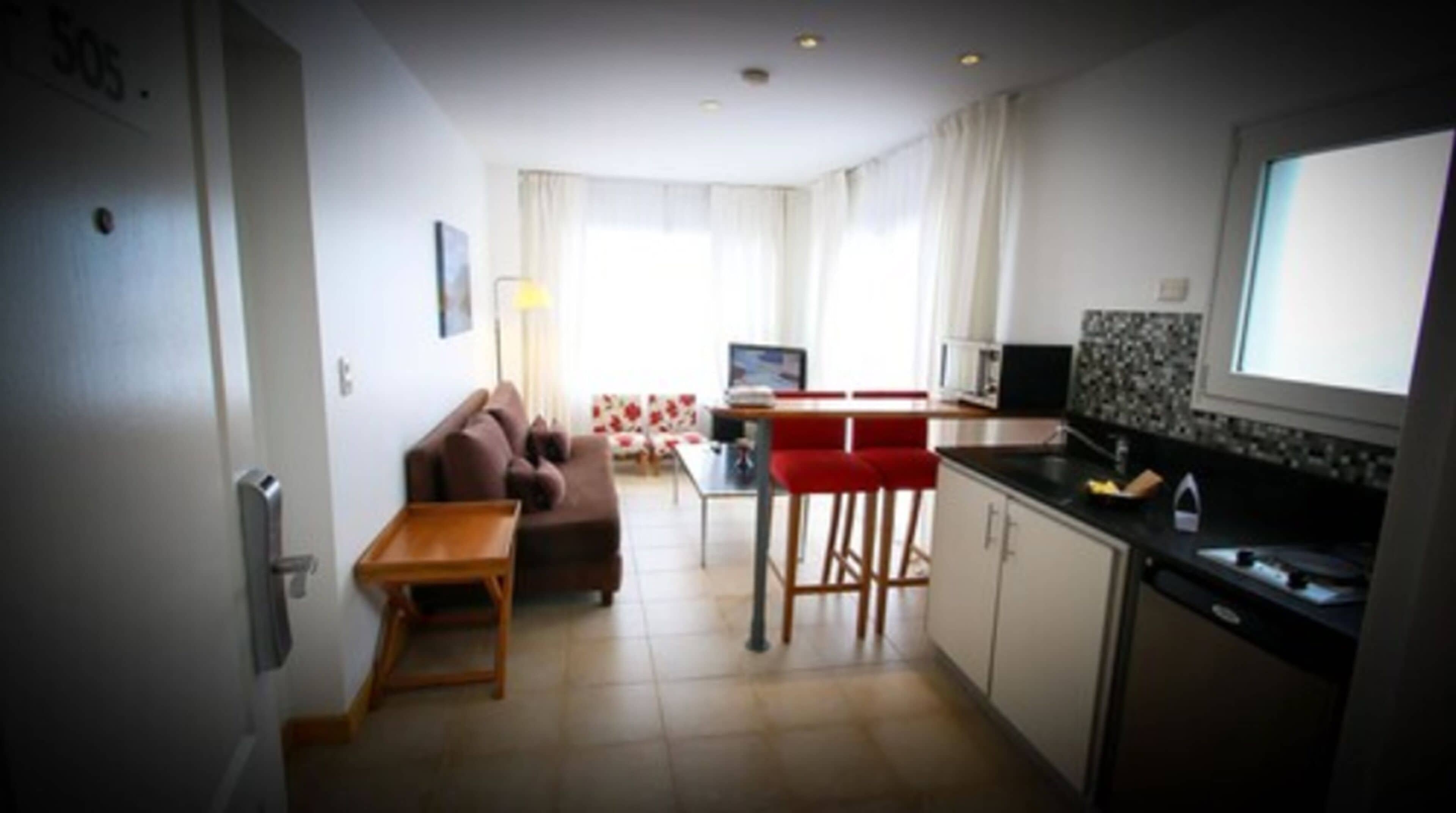 A compact living space with a kitchenette, a dining area, and a sofa.