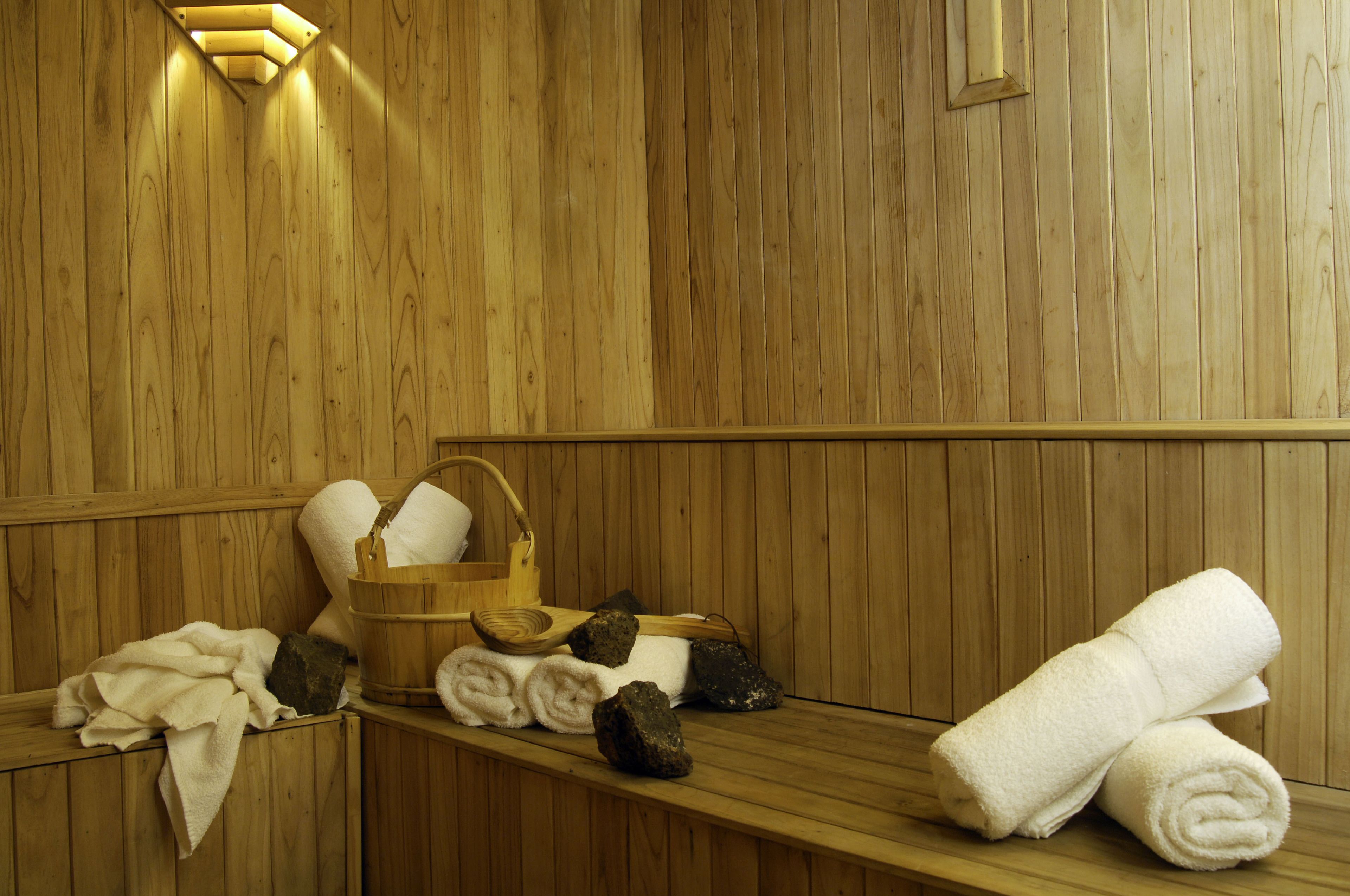 Una sauna de madera con toallas, un cesto y un banco de madera.