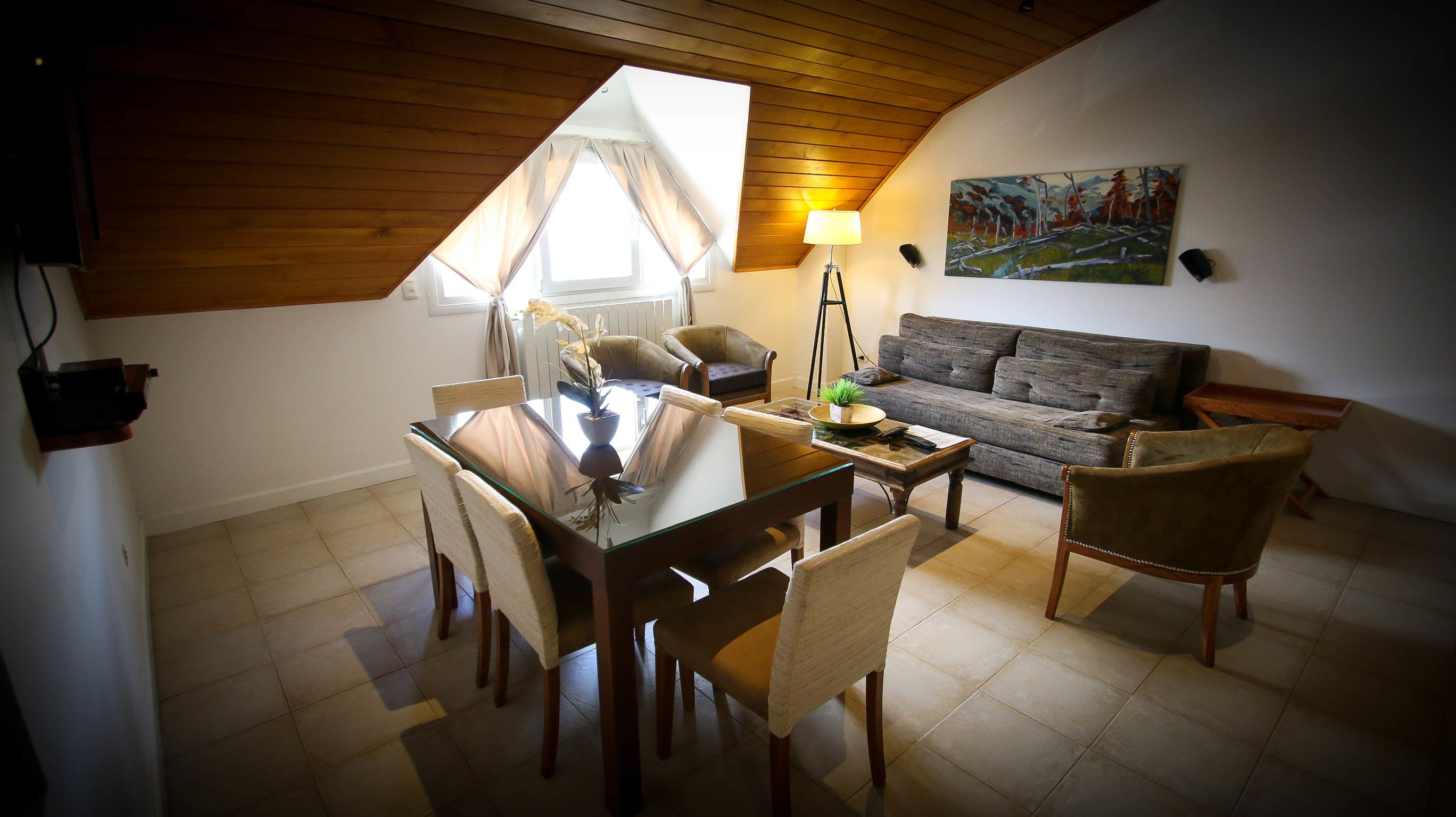 A cozy living room with a dining area, a sofa, and a painting on the wall.