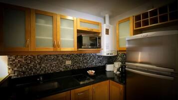 Una cocina con armarios de madera, microondas, refrigerador de acero inoxidable y salpicadero de azulejos.
