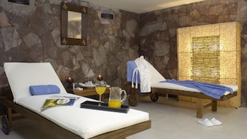 Relax in a serene spa room with two sun loungers, a side table, and a mirror.