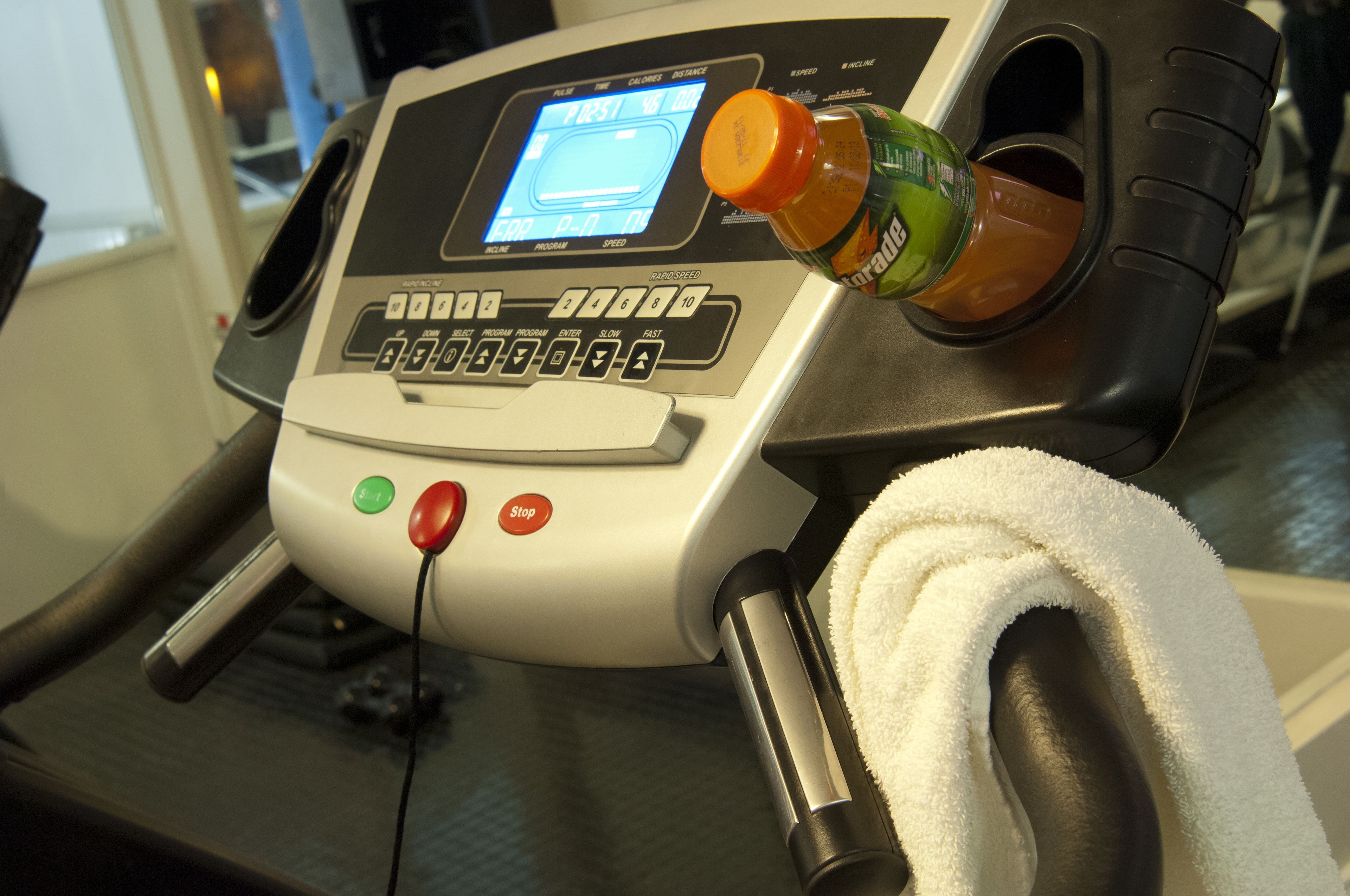 A treadmill with a digital display, control buttons, and a towel.