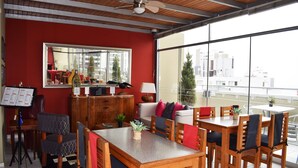 Un comedor con una mesa y sillas de madera, un espejo y vistas de la ciudad a través de amplios ventanales.