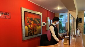 Zona de recepción de hotel con un mostrador de mármol, un cuadro abstracto enmarcado y un cartel que indica la habitación 73.