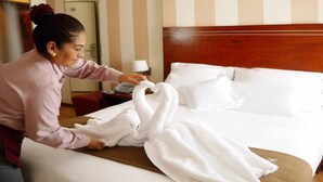 Una habitación de hotel con una cama, cabecera de madera y mesita de noche con lámpara.