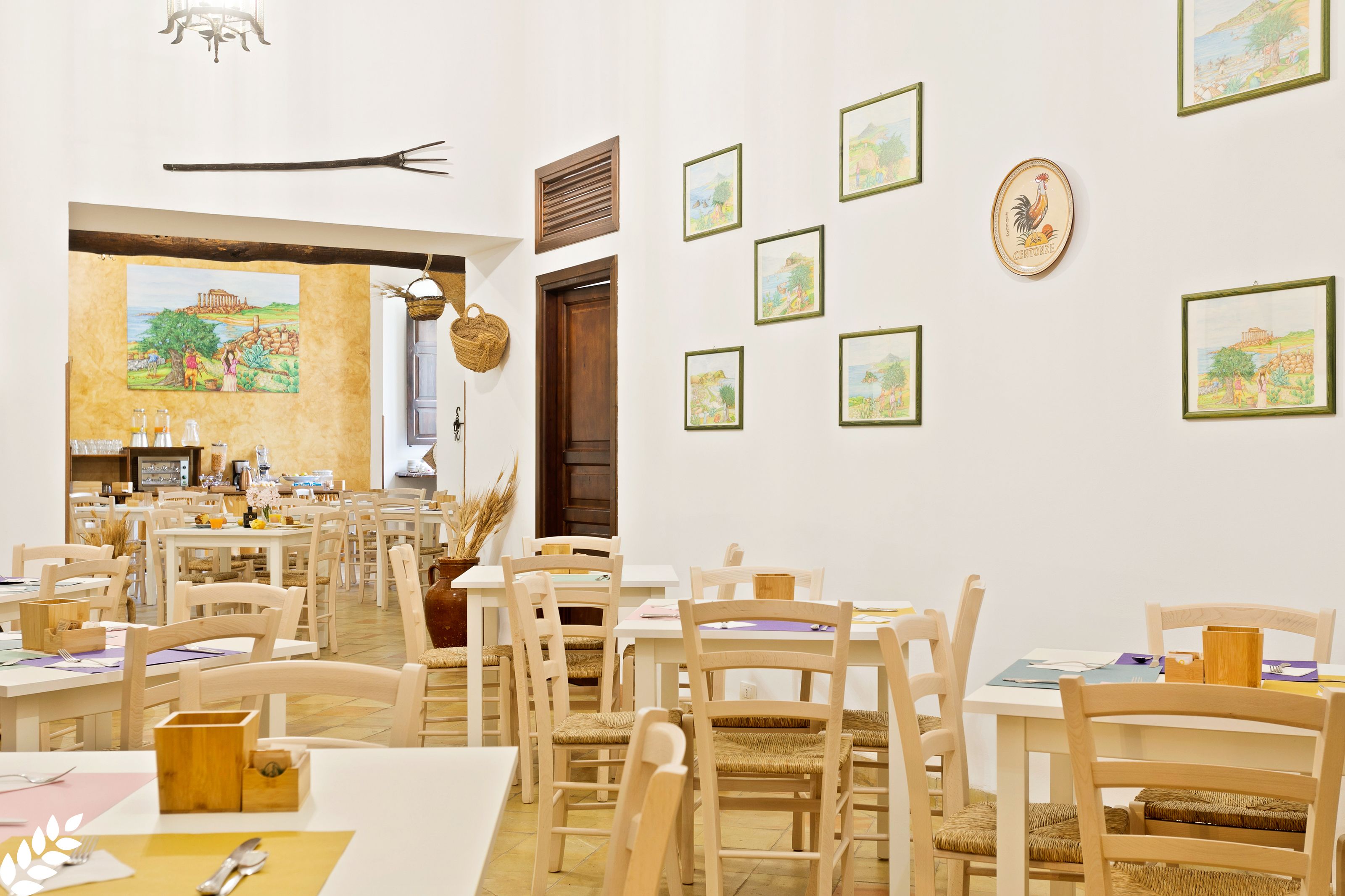 Un espace repas avec des tables et des chaises en bois, un mur orné de tableaux encadrés et une fresque murale.