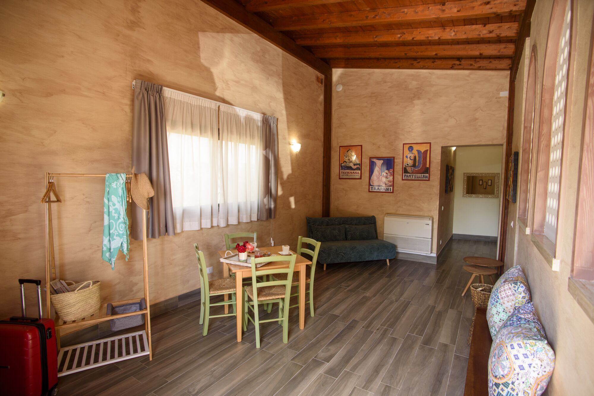 Una habitación acogedora con piso de madera, una mesa de comedor con sillas, un sofá y una ventana con cortinas.