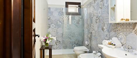 A bathroom with a shower, toilet, bidet, and sink.
