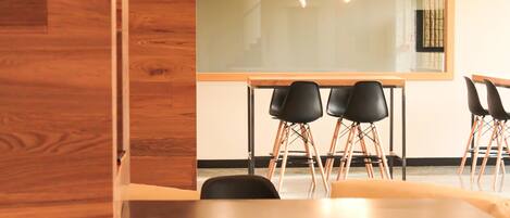 A conference room with a large table, four black chairs, and a modern chandelier.