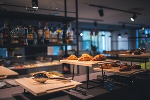 Un espace bar avec des étagères remplies de bouteilles d’alcool, des tables où sont servis des croissants, et un panneau indiquant un menu de croissants.