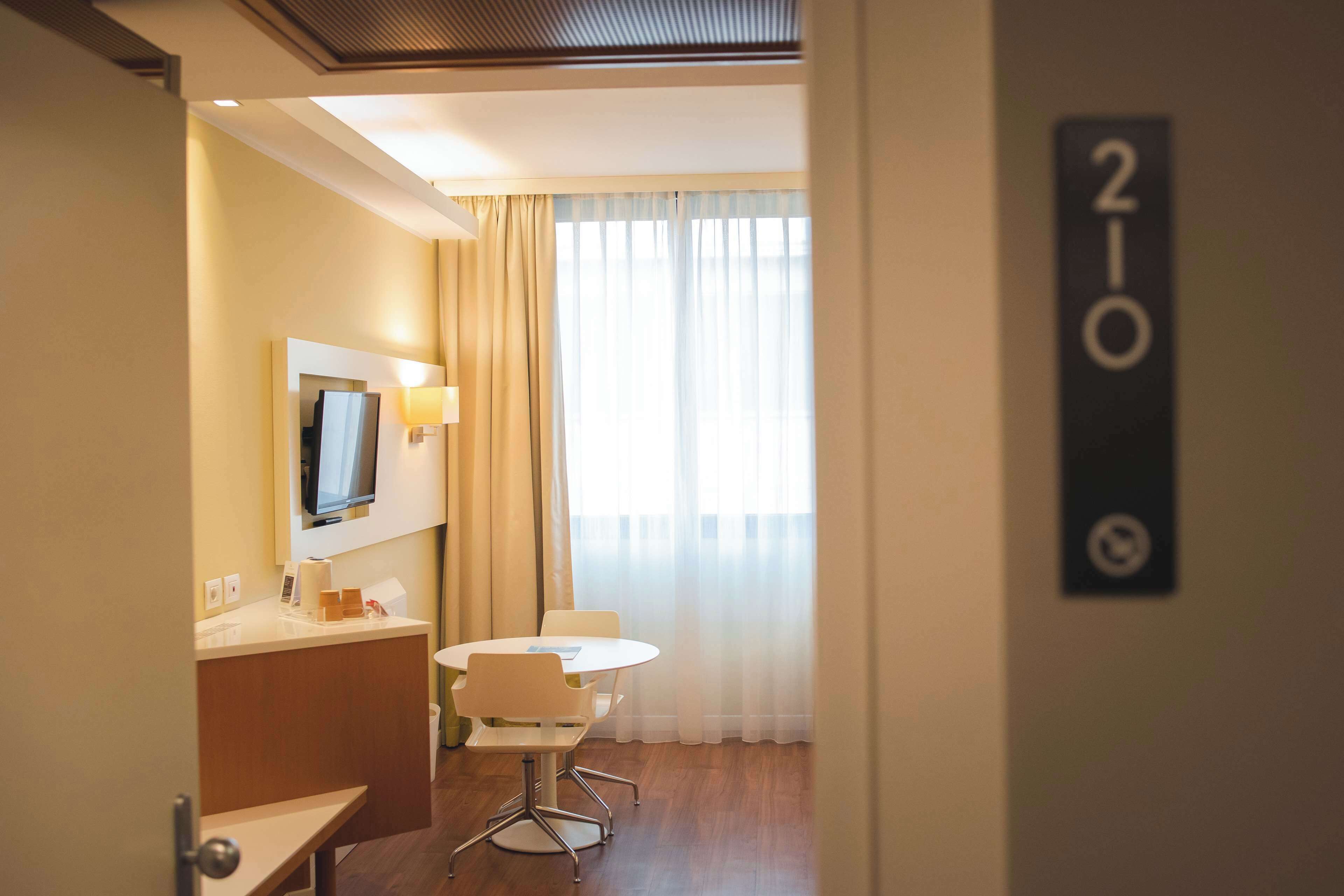 Una habitación de hotel con escritorio, silla y televisor montado en la pared.