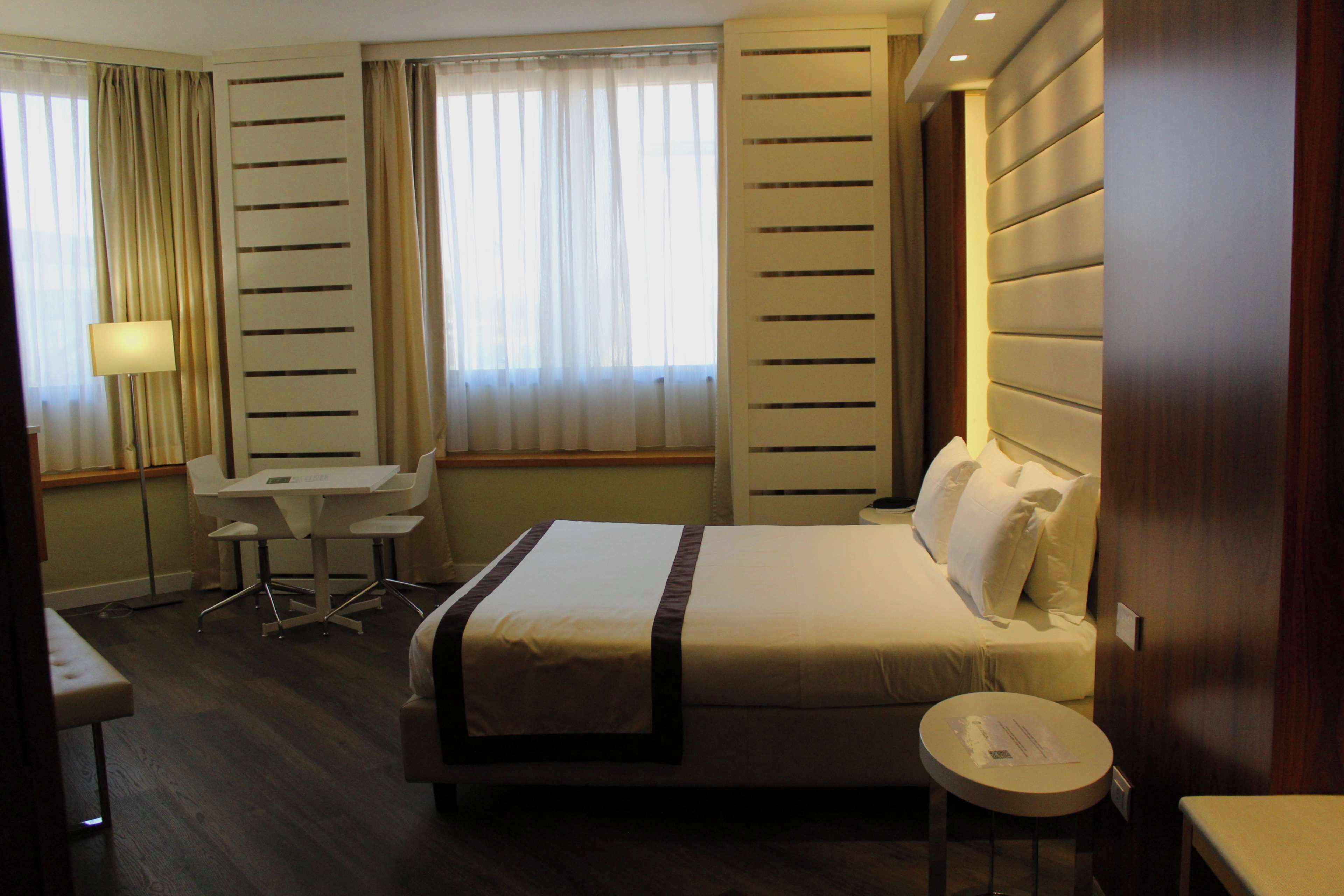 Una habitación de hotel con cama, escritorio, silla y una pequeña mesa.