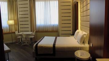 Una habitación de hotel con cama, escritorio, silla y una pequeña mesa.