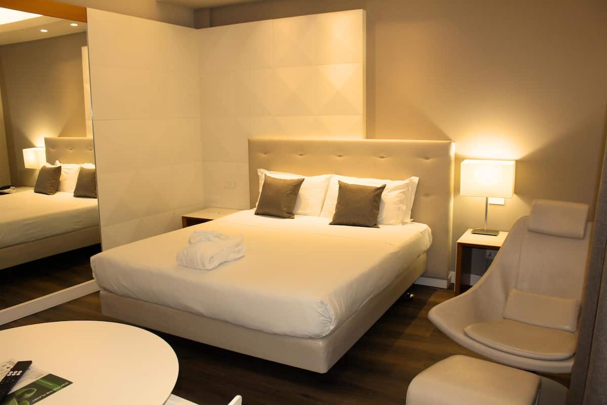 Een hotelkamer met een groot bed, een zithoek met een stoel en een kleine tafel.