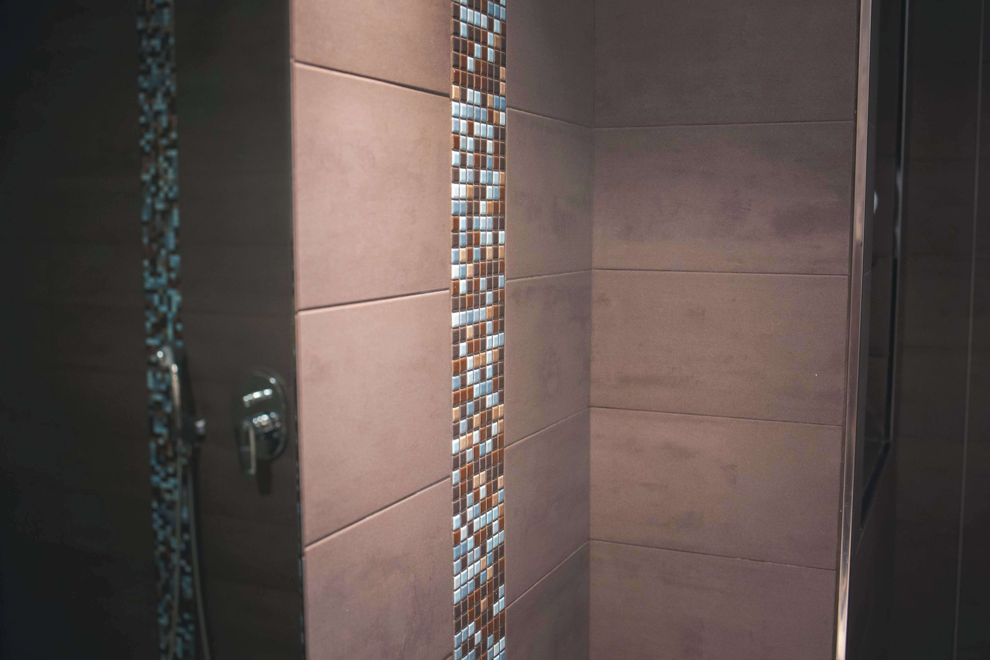 Esquina de una habitación con pared de azulejos y una puerta.