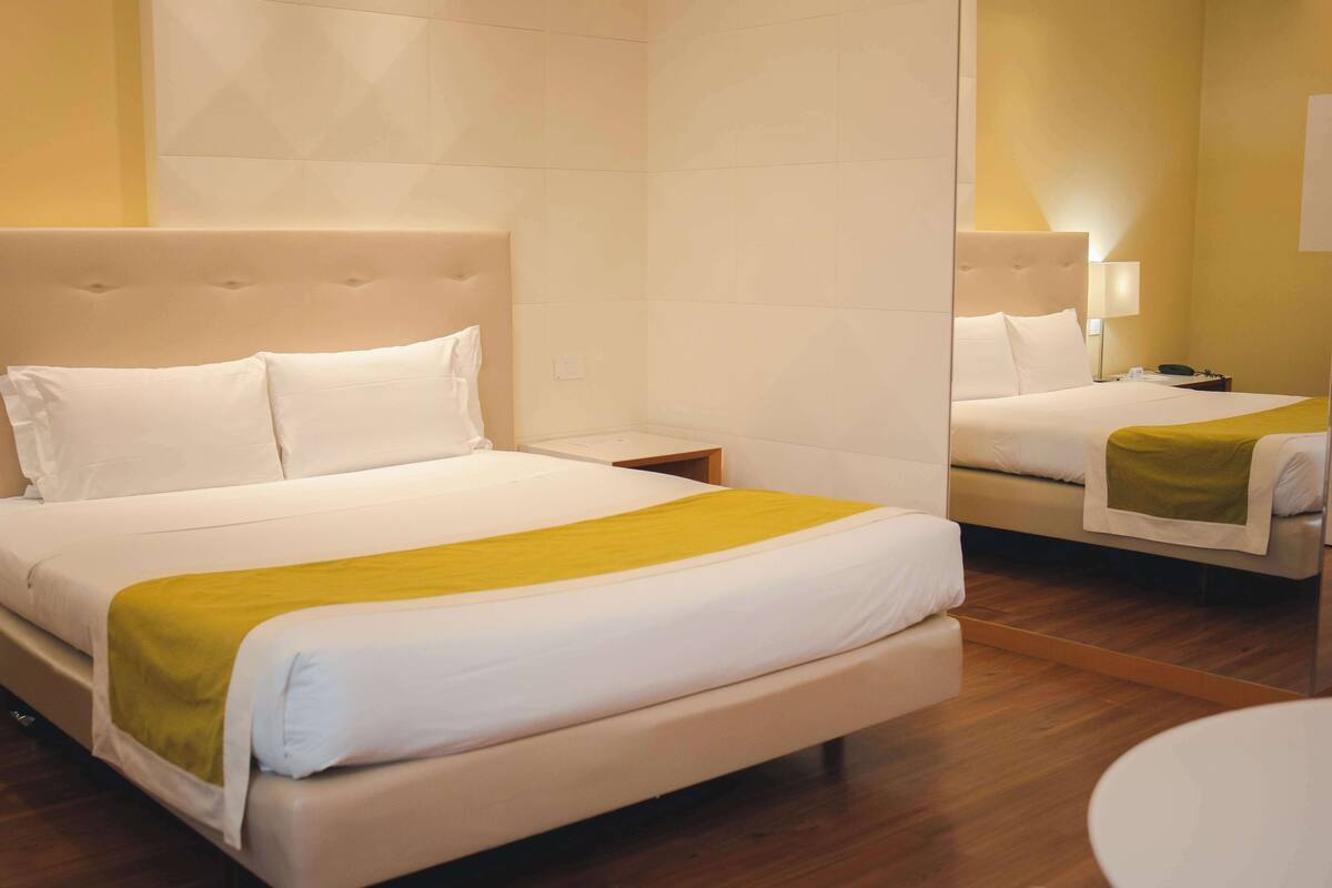 Een hotelkamer met een groot bed, een nachtkastje en een spiegel.