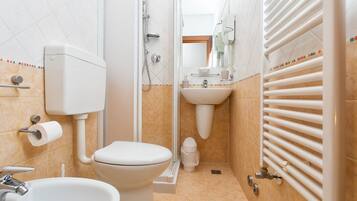 Een badkamer met toilet, wastafel, douche en een handdoekhouder.