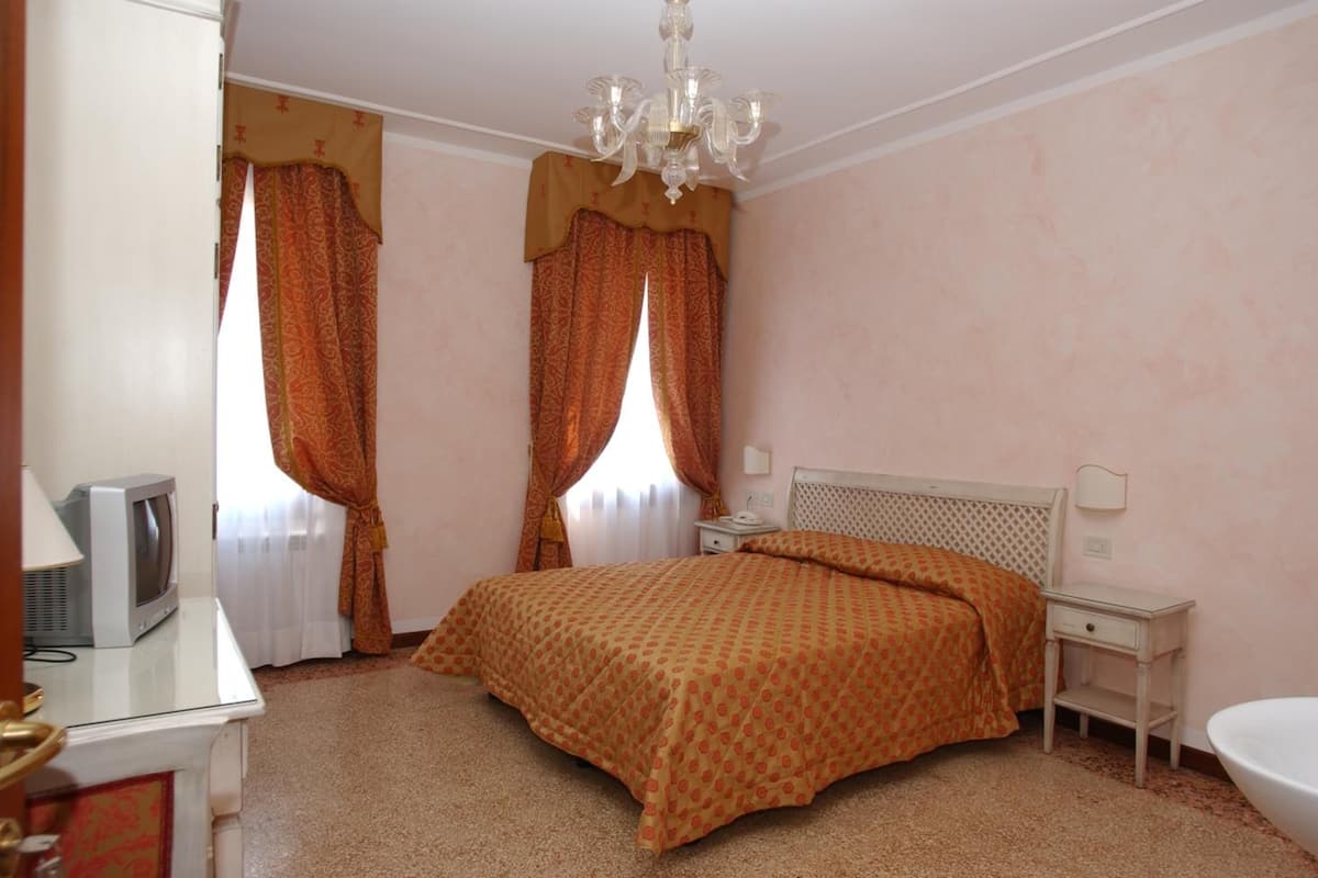 Une chambre à coucher avec un lit, une table de chevet, une lampe et un téléviseur.