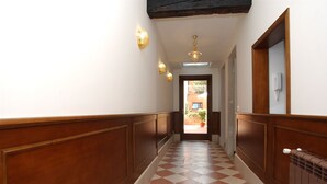 Un couloir doté d’un sol à carreaux, de lambris en bois et d’appliques murales.