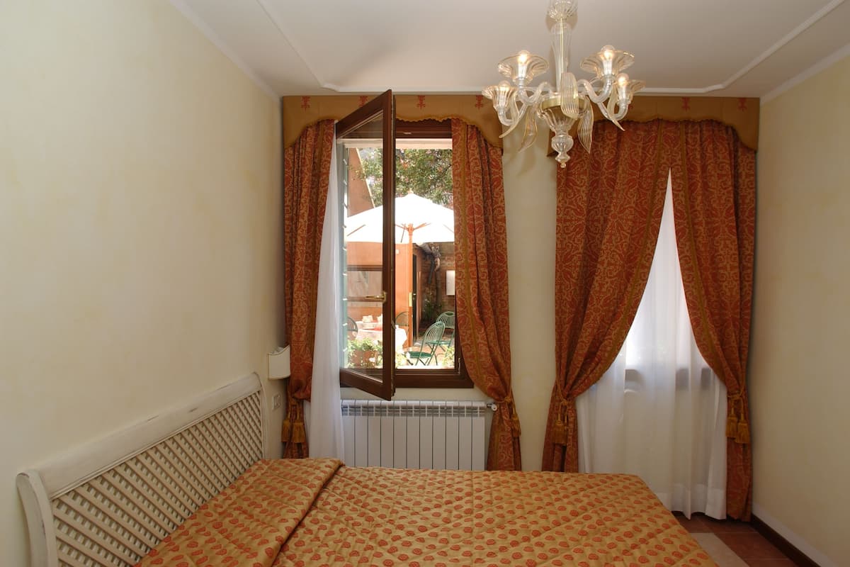 Une chambre à coucher avec un lit, un radiateur, une fenêtre avec des rideaux et un lustre.
