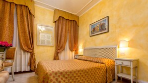 Une chambre d’hôtel avec un lit, une table de chevet, une chaise et une fenêtre avec des rideaux.
