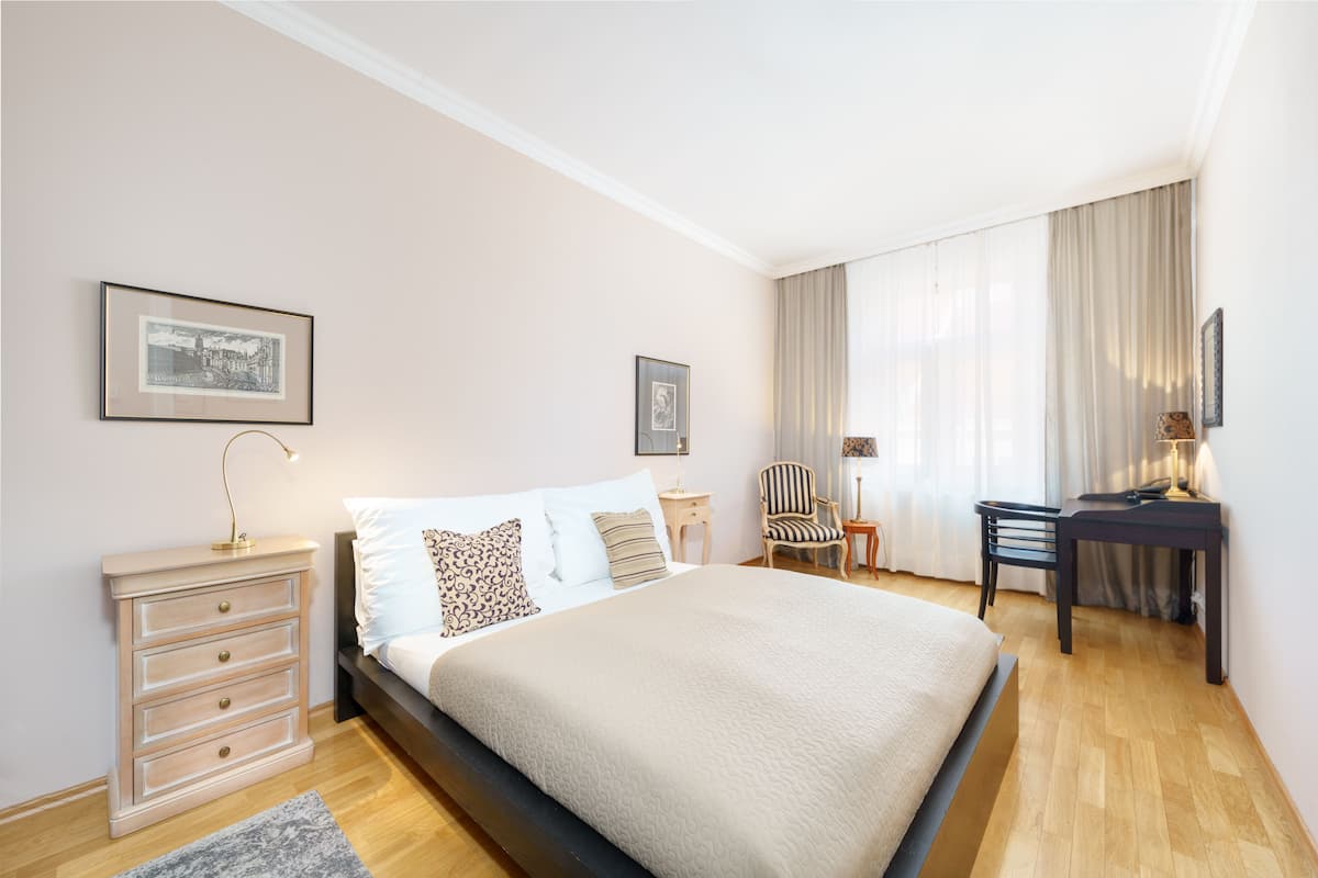 Ein ordentlich eingerichtetes Schlafzimmer mit Bett, Nachttischen, Schreibtisch und Stühlen.