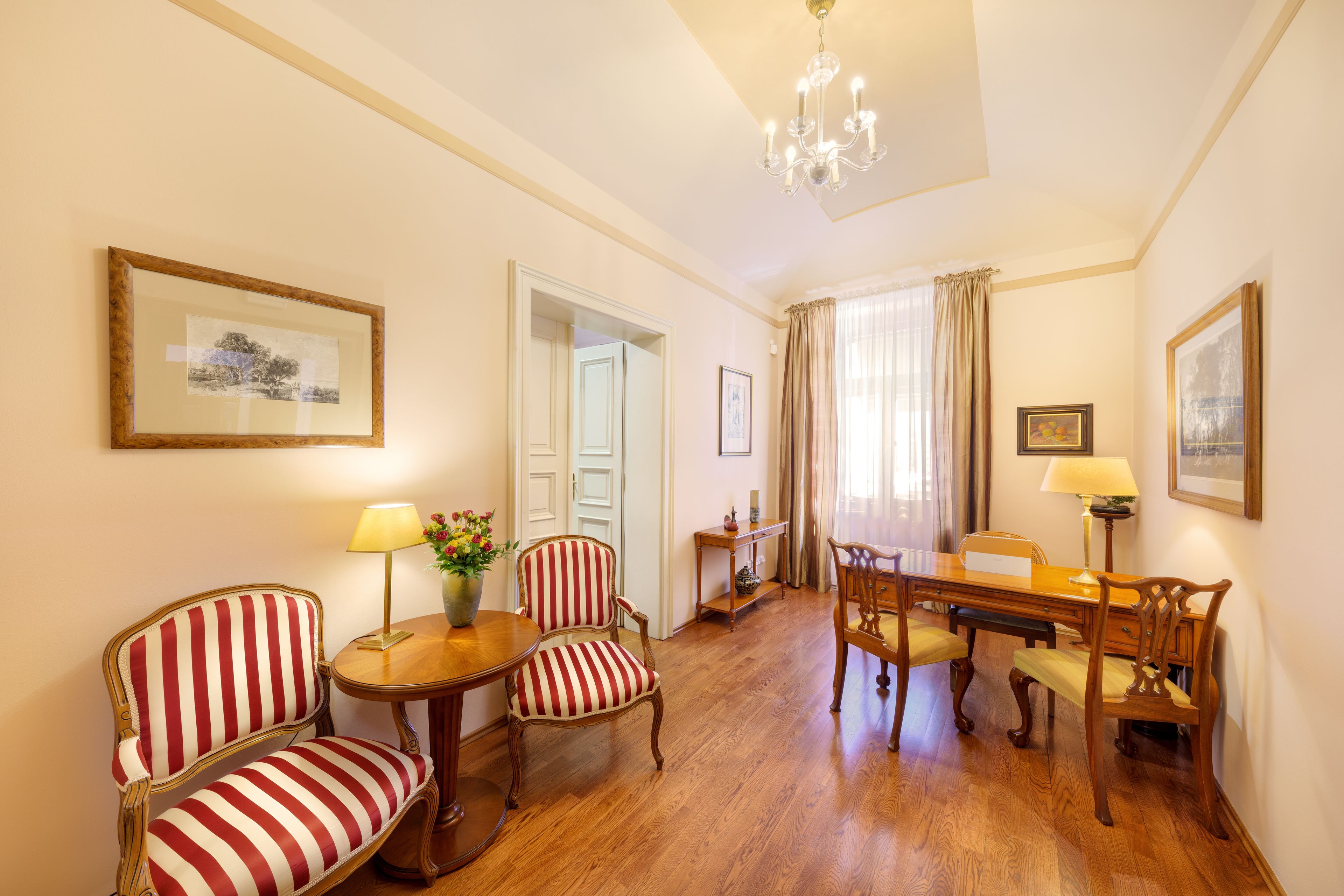 Una stanza con sedie a righe, un tavolo da pranzo in legno e un lampadario.