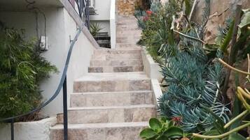 Un escalier en pierre menant à un balcon agrémenté de rampes en métal.