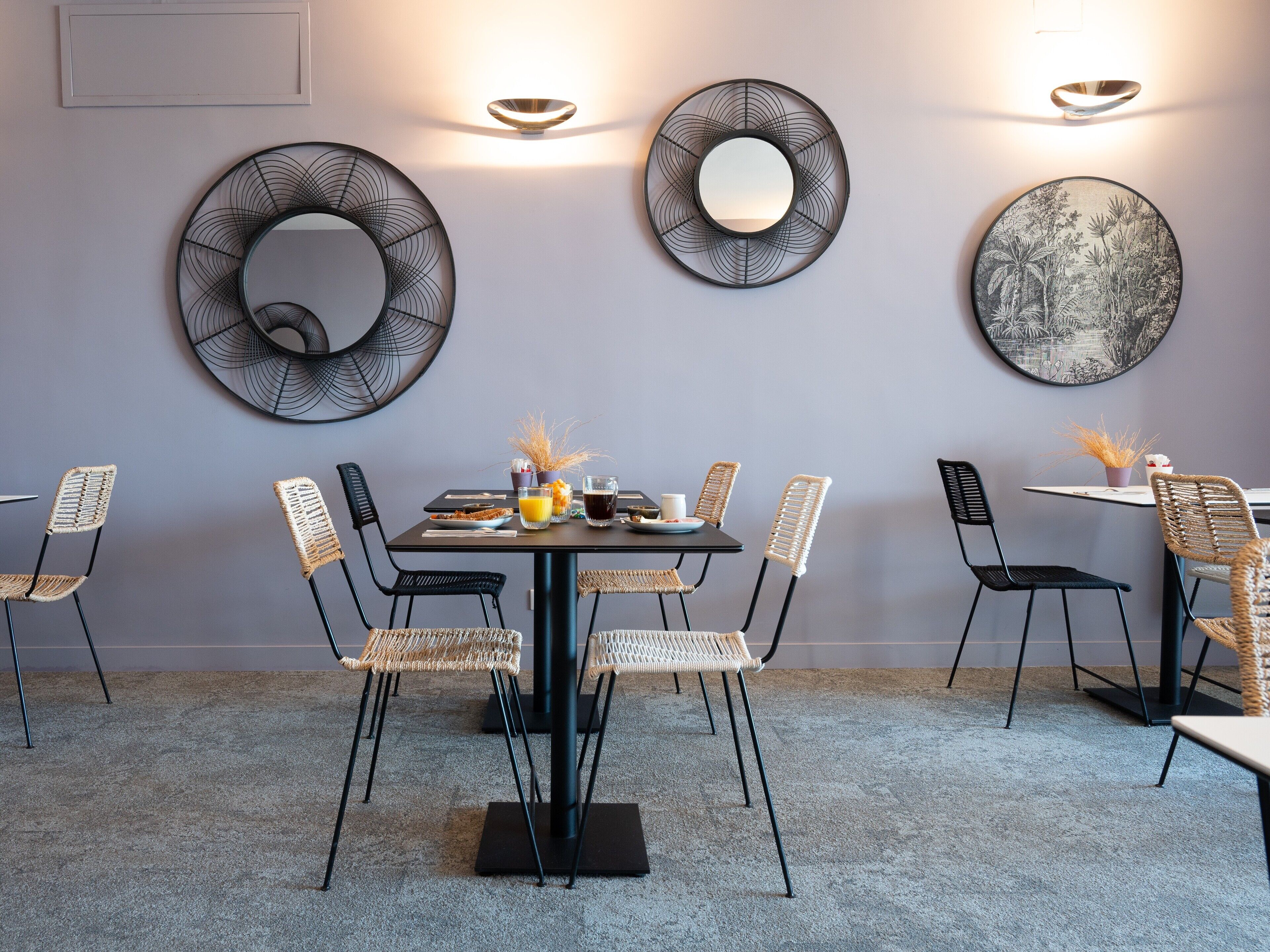 Un coin repas comprenant une table ronde, six chaises et des miroirs décoratifs fixés au mur.