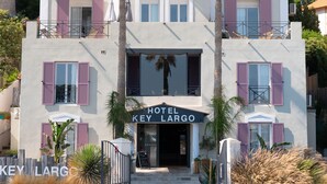 A two-story hotel with a central entrance, balconies, and palm trees. - Key Largo (Bandol)