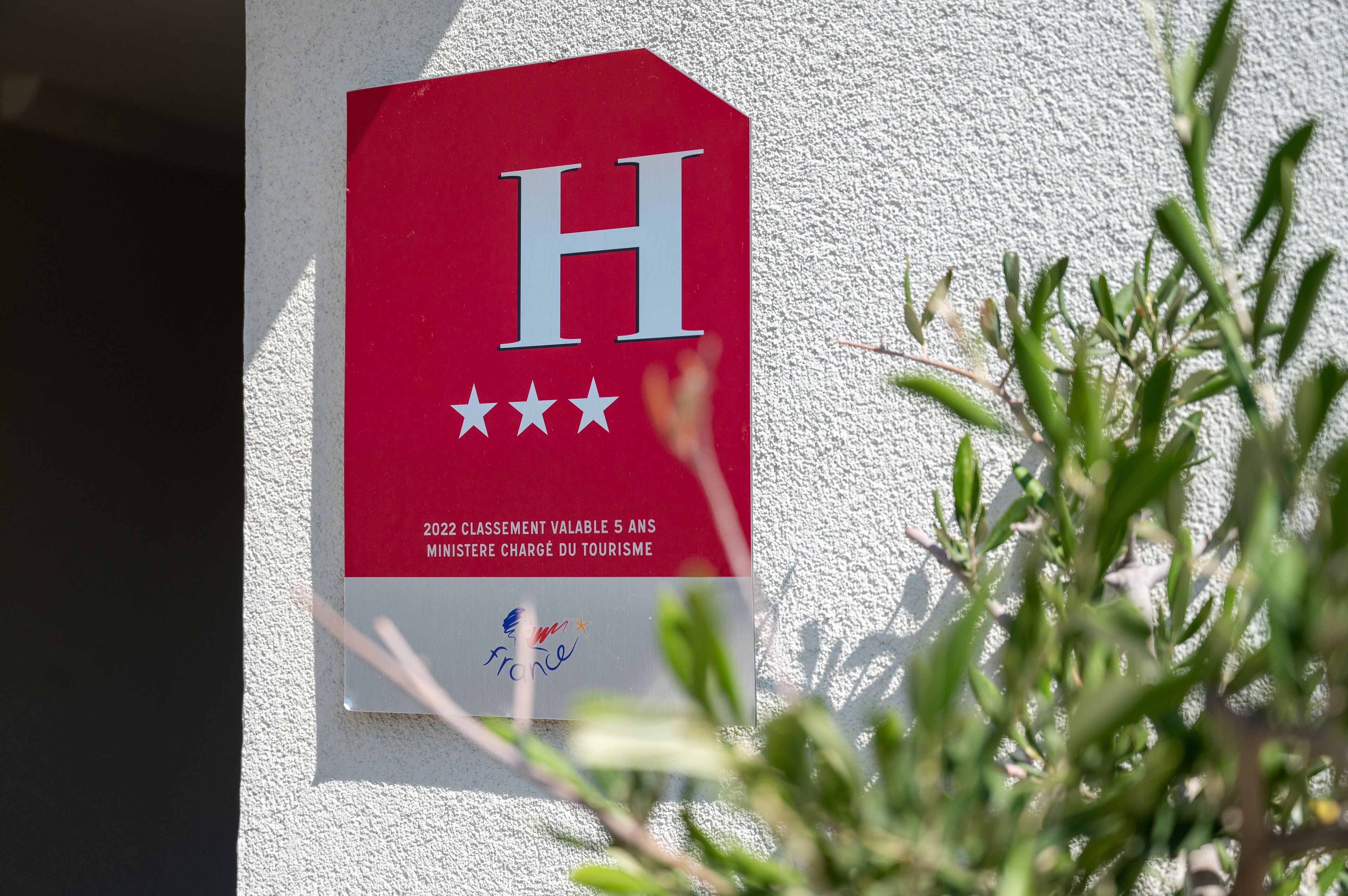 Una señal roja con una 'H' blanca y cinco estrellas, que indica un hotel.
