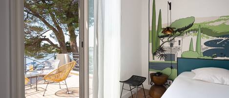 Una habitación de hotel con un ventanal grande, una cama, una silla y un mural en la pared.