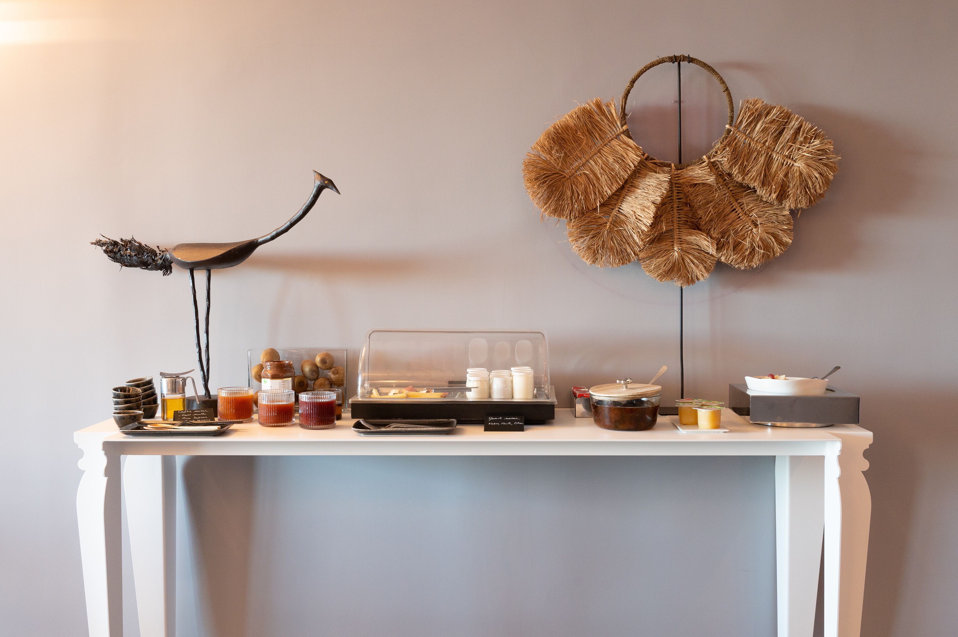 Una mesa blanca con una variedad de alimentos y condimentos para un bufé, frente a una pared lisa.