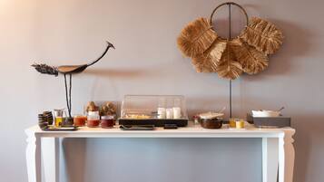 Una mesa blanca con una variedad de alimentos y condimentos para un bufé, frente a una pared lisa.