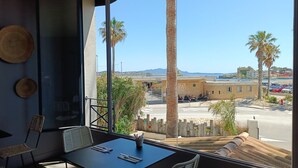 A balcony with a table and chairs, overlooking a coastal area with palm trees and a parking lot. - Key Largo (Bandol)
