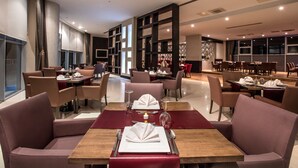 Un restaurant moderne doté de hauts plafonds, de grandes fenêtres et proposant différents types de sièges, notamment des tables et des banquettes.
