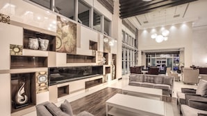 Un intérieur moderne doté d’un grand espace salon, d’étagères intégrées ornées d’objets décoratifs et offrant une vue sur le hall d’entrée.