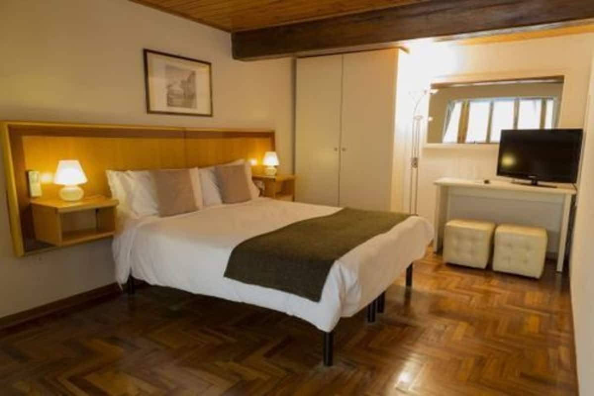 A bedroom with a bed, bedside lamps, a television, and a wardrobe.