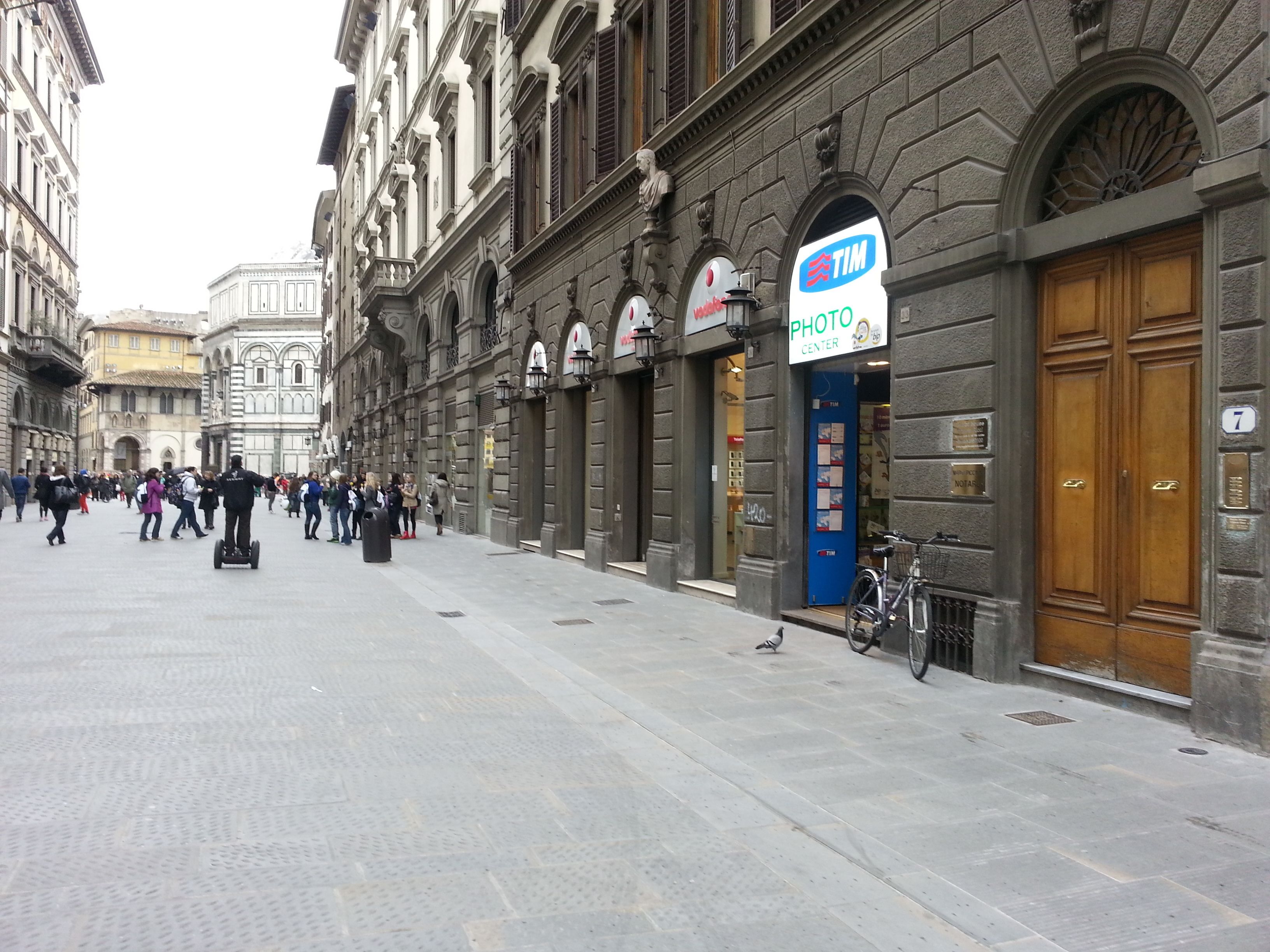 A historic street with a photo center, stone buildings, and a paved walkway.